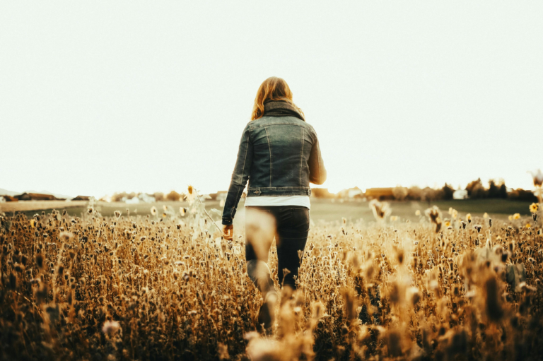Woman walking through a field during post-cancer recovery and healing