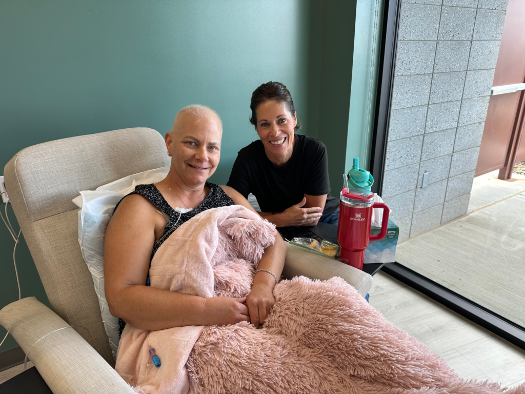 Sitting in a chemotherapy treatment chair during cancer treatment with a support person nearby