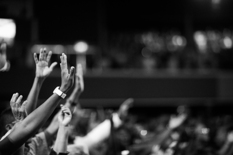 Woman worshiping with hands lifted in a treatment room, symbolizing faith, hope, and trust in God during cancer treatment.