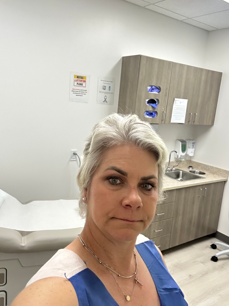 Woman in medical exam room after cancer treatment, moments after being told she is cancer free